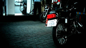 黑色Yamaha機車夜晚停泊在鵝卵石街道上，靠近加油站。 — 改裝摩托車 壁紙