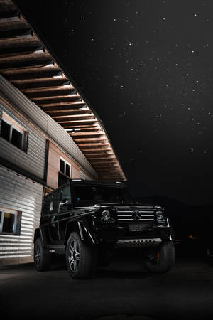 黑色豪華SUV在星空下夜間停泊在現代建築旁。 — Mercedes Benz C300 壁紙
