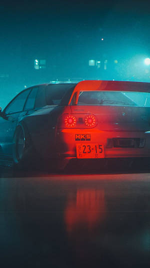 黑色甩尾車在霓虹燈下夜間濕滑街道上亮起紅色尾燈。 — 深色手機 壁紙