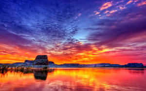湖上壯麗的夕陽，水中倒映著色彩斑斕的雲彩和岩層。 — 日落 壁紙