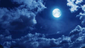 滿月在夜空中透過深藍色的雲層閃耀。 — 黑夜 壁紙
