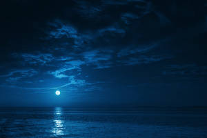 滿月在多雲的夜空下照耀著平靜的海水。 — 夜空 壁紙