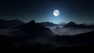 星空下，月光照耀的山脈，山谷中瀰漫著薄霧。 — 深色主題 壁紙