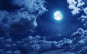 滿月在夜間穿過深藍色雲層閃耀。 — 月光 壁紙