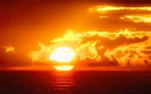 海洋上空的夕陽，天空和海水呈現熾熱的橙色和紅色 — 日落 壁紙