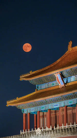 一輪橙色滿月在夜間升起在傳統中國宮殿屋頂上方。 — 月光 壁紙