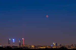 粉紅月亮在夜間升起在馬德里發光的摩天大樓之上。 — 火星人布魯諾 壁紙