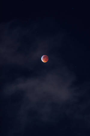血月穿過暗夜雲層升起，星光可見。 — 月光 壁紙