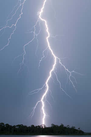 一道強烈的閃電照亮了湖泊和森林上空的暴風雨天空。 — 閃電麥坤 壁紙