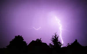 閃電擊中屋頂和樹木，背景是紫色暴風雨天空。 — 紫色 壁紙