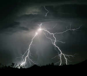強烈的閃電照亮了黑暗山丘上方的暴風雨夜空。 — 閃電麥坤 壁紙