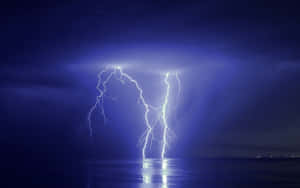 閃電照亮了夜晚平靜的海面上方黑暗暴風雨的天空。 — 閃電 壁紙
