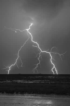 一道強大的閃電照亮了平坦田野上空黑暗的暴風雨天空。 — 小米平板 8 Pro 壁紙