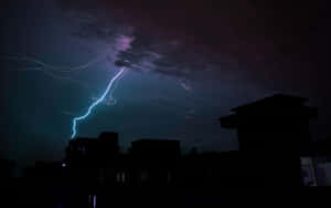 閃電擊中暴風雨夜空下黑暗的城市屋頂。 — 閃電 壁紙