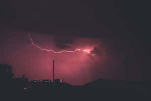 粉紅色閃電照亮了黑暗城市屋頂上方的暴風雨之夜。 — 閃電麥坤 壁紙