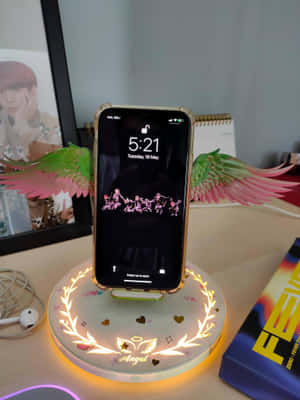 帶有天使翅膀和發光底座的電話放在桌上，還有扇子裝飾。 — iPad 第9代 壁紙