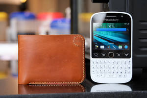 反光桌面上的白色BlackBerry手機和棕色皮革錢包。 — 黑莓 壁紙