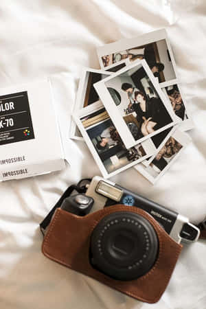 白色床罩上的Instax相機和即時照片。 — 拍立得 壁紙