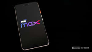 智慧型手機在暗色螢幕上顯示HBO Max標誌，帶有柔和光線。 — HBO 壁紙