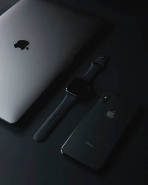 黑色 Apple iPhone、Apple Watch 和銀色 MacBook 在深色表面上