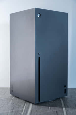 灰色瓷磚地板上的時尚黑色 Xbox Series X 遊戲主機。 — IQOO Pad5 Pro 壁紙