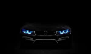 黑暗中帶有發光藍色頭燈的黑色BMW汽車。 — 好看汽車 壁紙