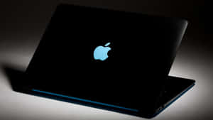 工作室燈光下帶有發光藍色Apple標誌的黑色筆記型電腦 — 最佳筆電 壁紙
