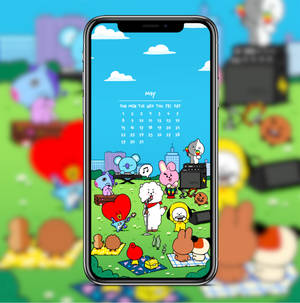 手機螢幕顯示BT21角色在公園演奏音樂，並帶有五月日曆。 — Pixel 10 Pro Fold 壁紙