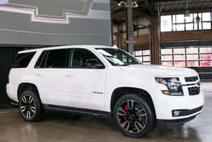 白色雪佛蘭Tahoe SUV，黑色輪圈和紅色制動器，在現代工業車庫中。 — 低調 壁紙