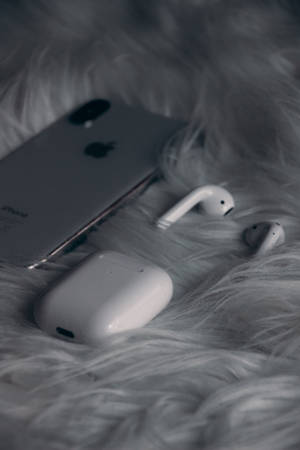 銀色iPhone和白色AirPods保護殼在蓬鬆灰色地毯上。 — 白色 iPhone 壁紙