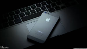 昏暗燈光下筆記型電腦鍵盤上的銀色iPhone