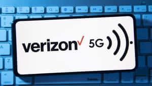 智慧型手機在藍色鍵盤上顯示 Verizon 5G 標誌 — 威訊 壁紙