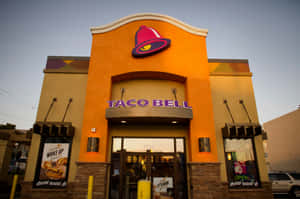 黃昏時分的Taco Bell餐廳外觀，設有發光招牌和得來速窗口。 — 塔可 壁紙