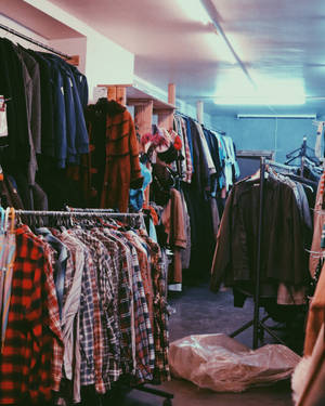 在昏暗的店內，螢光燈下掛滿復古服裝的衣架。 — 90年代 壁紙
