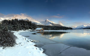藍天下冰凍湖面上的雪屋，以山為背景 — 冬季風景 壁紙