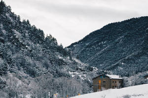 雪山谷中的石屋與常綠樹 — 冬季風景 壁紙