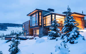 現代小屋在夜間白雪皚皚的山景中溫暖地發光。 — 冬季風景 壁紙