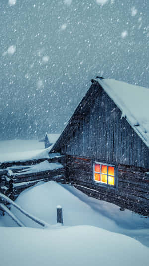 被雪覆蓋的小屋，在冬季風暴中窗戶發光 — 冬季風景 壁紙
