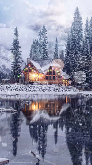 舒適的小屋，溫暖的燈光在結冰的湖中反射，雪黃昏的天空下。 — 冬季房屋 壁紙