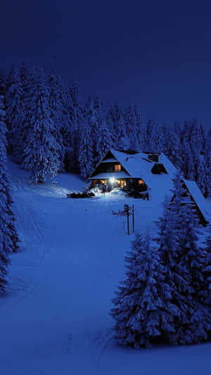 冬夜森林中帶有溫暖燈光的雪中小屋。 — 冬季風景 壁紙