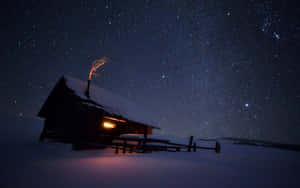 在雪白的冬天，一間舒適的小屋在星空下從窗戶透出溫暖的光芒。 — 夜晚 壁紙