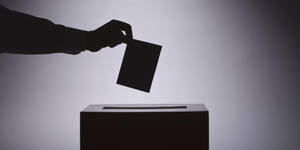 一隻剪影手將選票投入投票箱。 — 選舉 壁紙