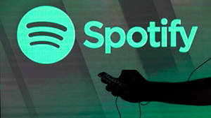 手在發光的Spotify標誌投影前拿著手機。 — Spotify 壁紙