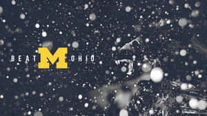 一頭獅子在飄落的雪中咆哮，旁邊是「BEAT OHIO」文字和黃色「M」標誌。 — 大學美式足球 壁紙