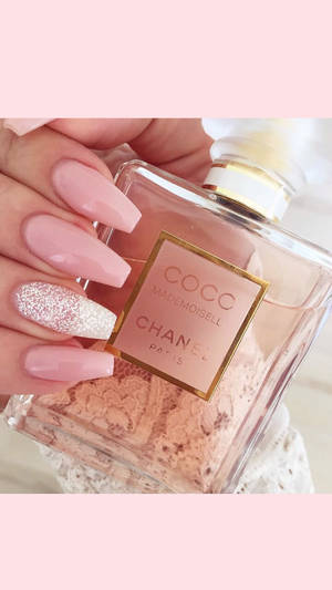 帶有粉紅色亮片指甲的手拿著 Chanel 香水瓶。 — 指甲 壁紙