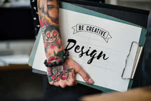 紋身的手拿著寫有「Be Creative Design」文字的寫字板。 — 美學 壁紙