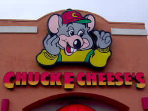 Chuck E Cheese's的吉祥物老鼠從建築物上色彩繽紛的招牌揮手。 — 查克芝士 壁紙