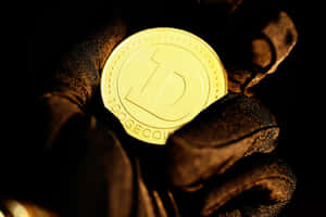 戴黑色手套的手在黑暗中握著金色Dogecoin。 — 狗狗藝術 壁紙