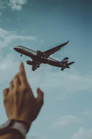 一個人的手指向天空中一架飛行的飛機。 — 簡約 壁紙