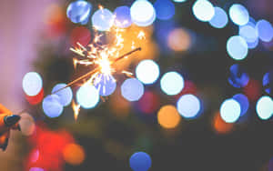手拿著仙女棒，背景有彩色模糊燈光。 — 新年快樂 壁紙